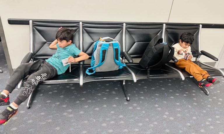 Kid waiting at baggage claim exhausted but calm from a planned family trip